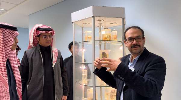 عضو هيئة تدريس يعرض عينات علم الأمراض في خزانة عرض لطلاب المدارس الزائرين