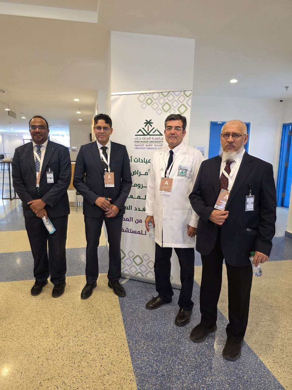 أعضاء هيئة التدريس مع لافتة مركز الملك خالد الجامعي الطبي